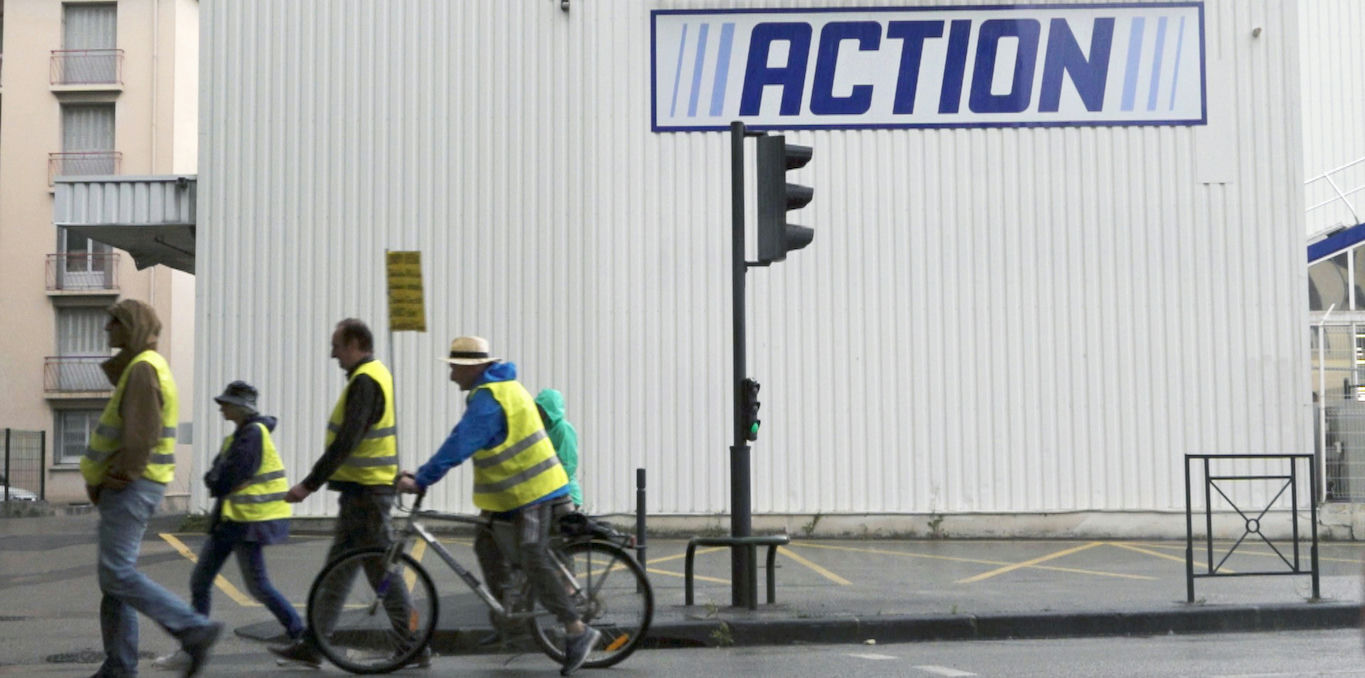 photo de quatre personnes portant un gilet jaune marchant devant un magasin action