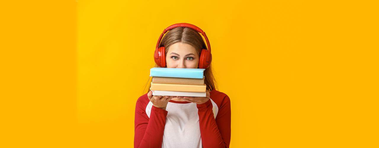 Jeune femme portant un casque audio rouge et tenant trois livres dans ses mains devant son visage