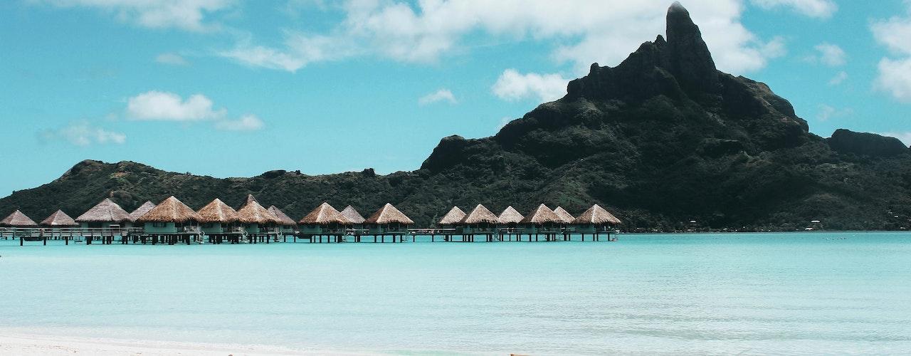 photo de plage avec des parasols blancs en arrière plan et une montagne