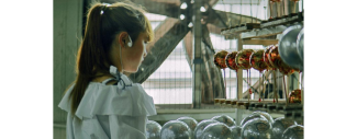 photo d'une petite fille de dos devant une machine pour fabriquer des boules de noel