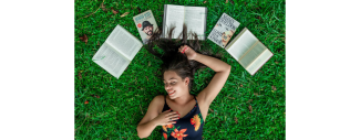 femme couchée sur l'herbe avec des livres autour de sa tête
