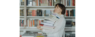 Photo d'une femme portant une pile de livres dans une librairie